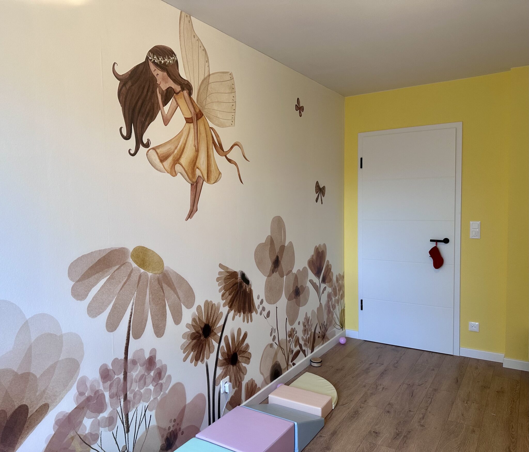 Réalisation en décoration d’intérieur d’une chambre d’enfant avec mur panoramique féerique, mur jaune et sol effet bois